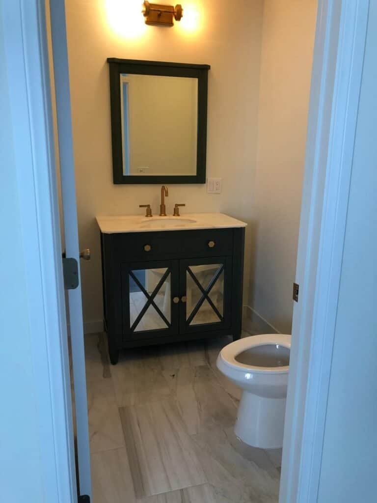 Bathroom renovation featuring stylish dark vanity with gold accents and a fresh, modern look.