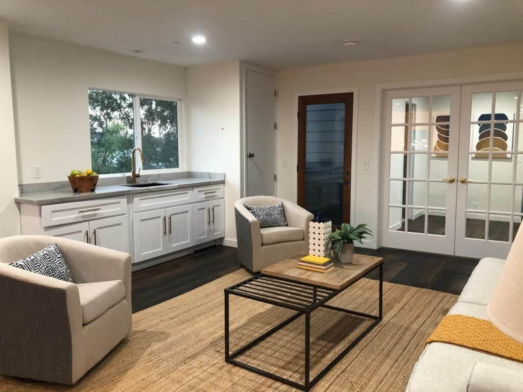 Bright, stylish kitchen with white cabinetry, large window, and contemporary living room accents.