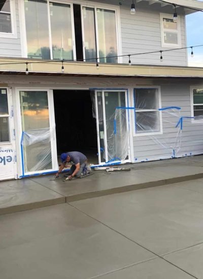 Workers pouring and smoothing concrete on backyard patio.